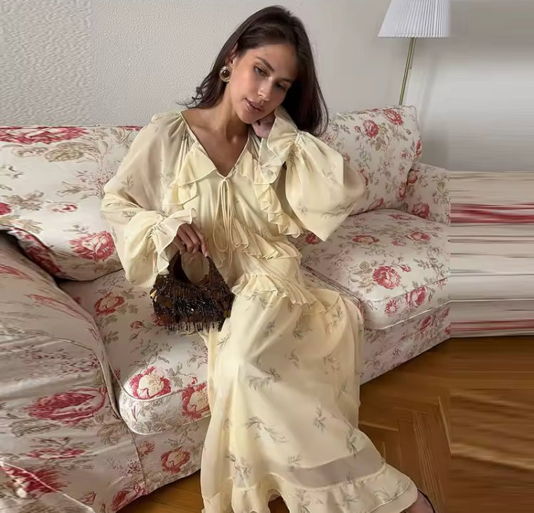 Frilly Maxi Dress - V-neck Ruffle A-line Dress in soft yellow with long sleeves, worn by model on floral couch. Elegant autumn fashion by Syntyche.